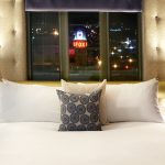 Padre Hotel guest room bed with window behind the pillow that shows The Fox Theatre sign lit up