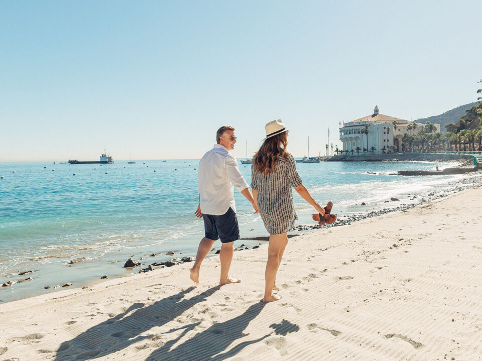 Couple walking on the beach with view of the Catalina Island casino in the background