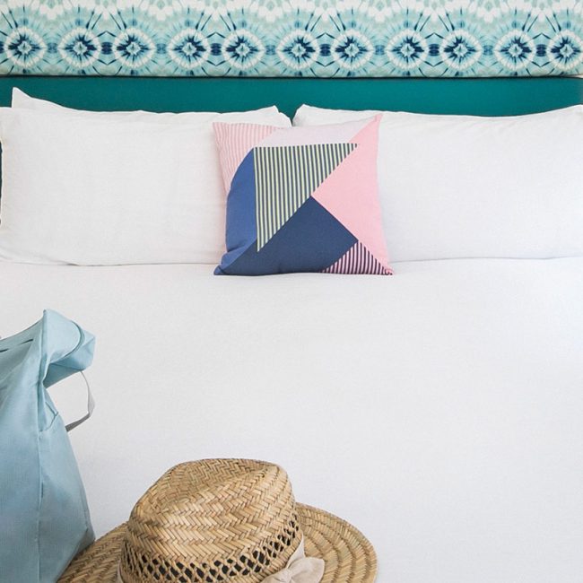 Shot of Bellanca Hotel guest room with tie dye headboard and beach hat on bed