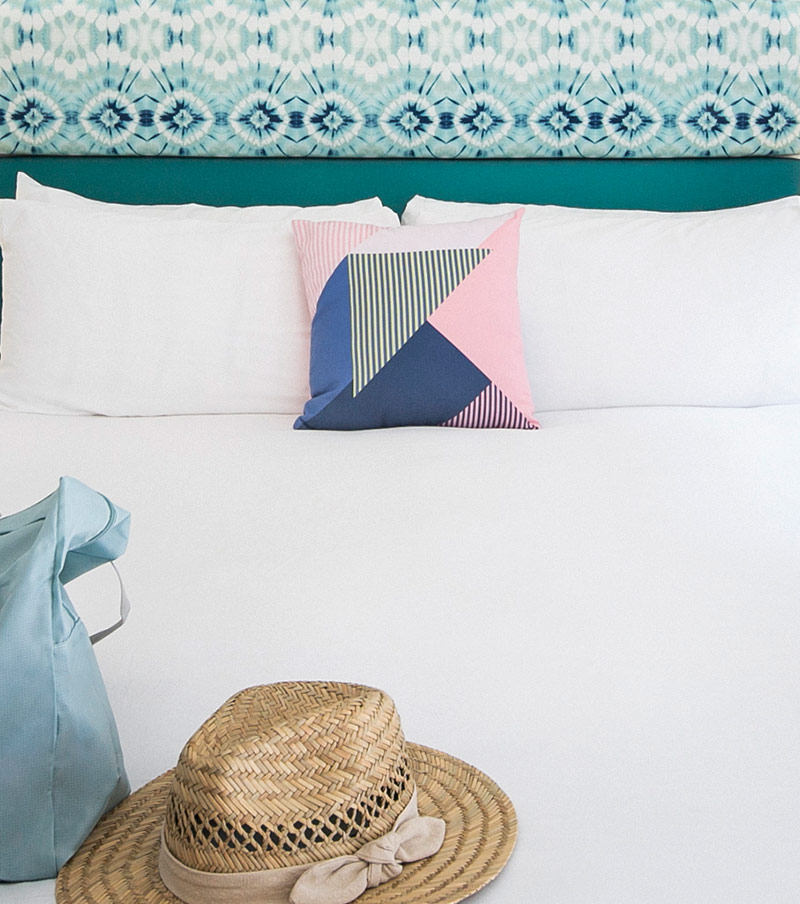 Shot of Bellanca Hotel guest room with tie dye headboard and beach hat on bed