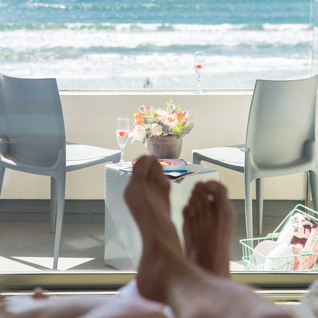Feet on bed overlooking the balcony off of a Tower23 suite with view of ocean
