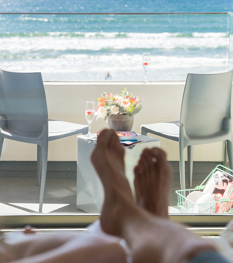 Feet on bed overlooking the balcony off of a Tower23 suite with view of ocean